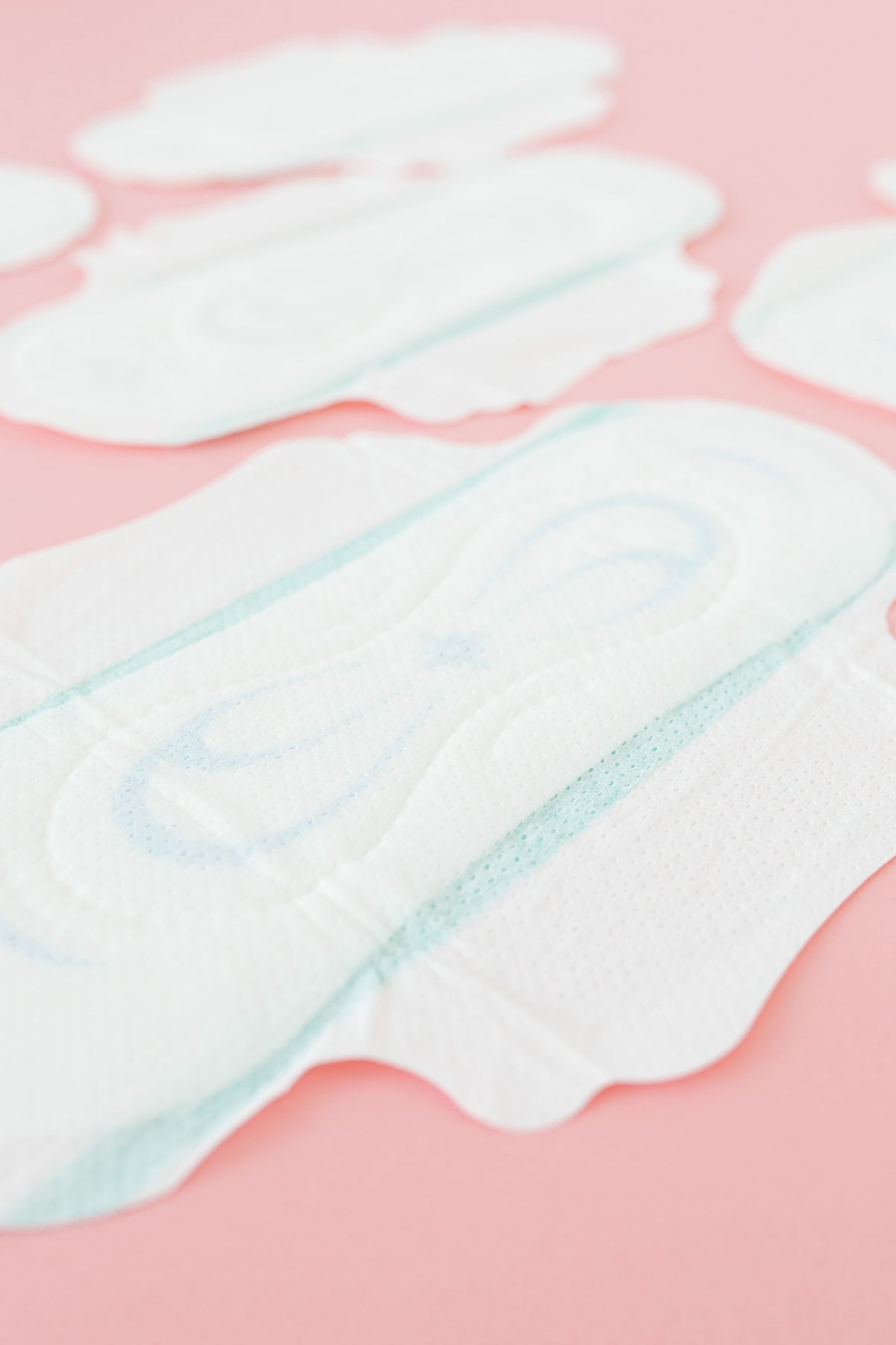 White sanitary pads arranged on a soft pink surface